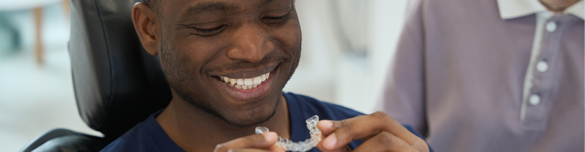 smiling man holding clear aligner